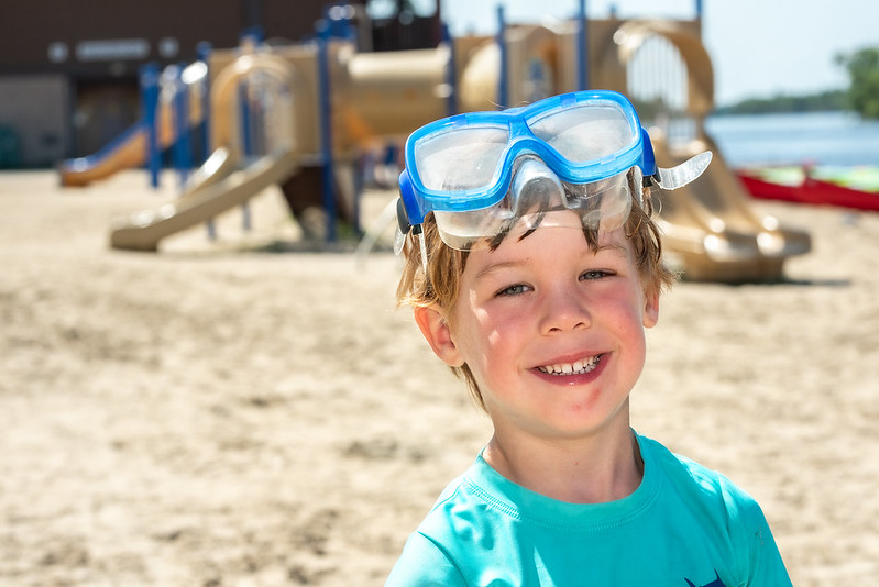 Image of boy on a beach with blue swim goggles on his forehead