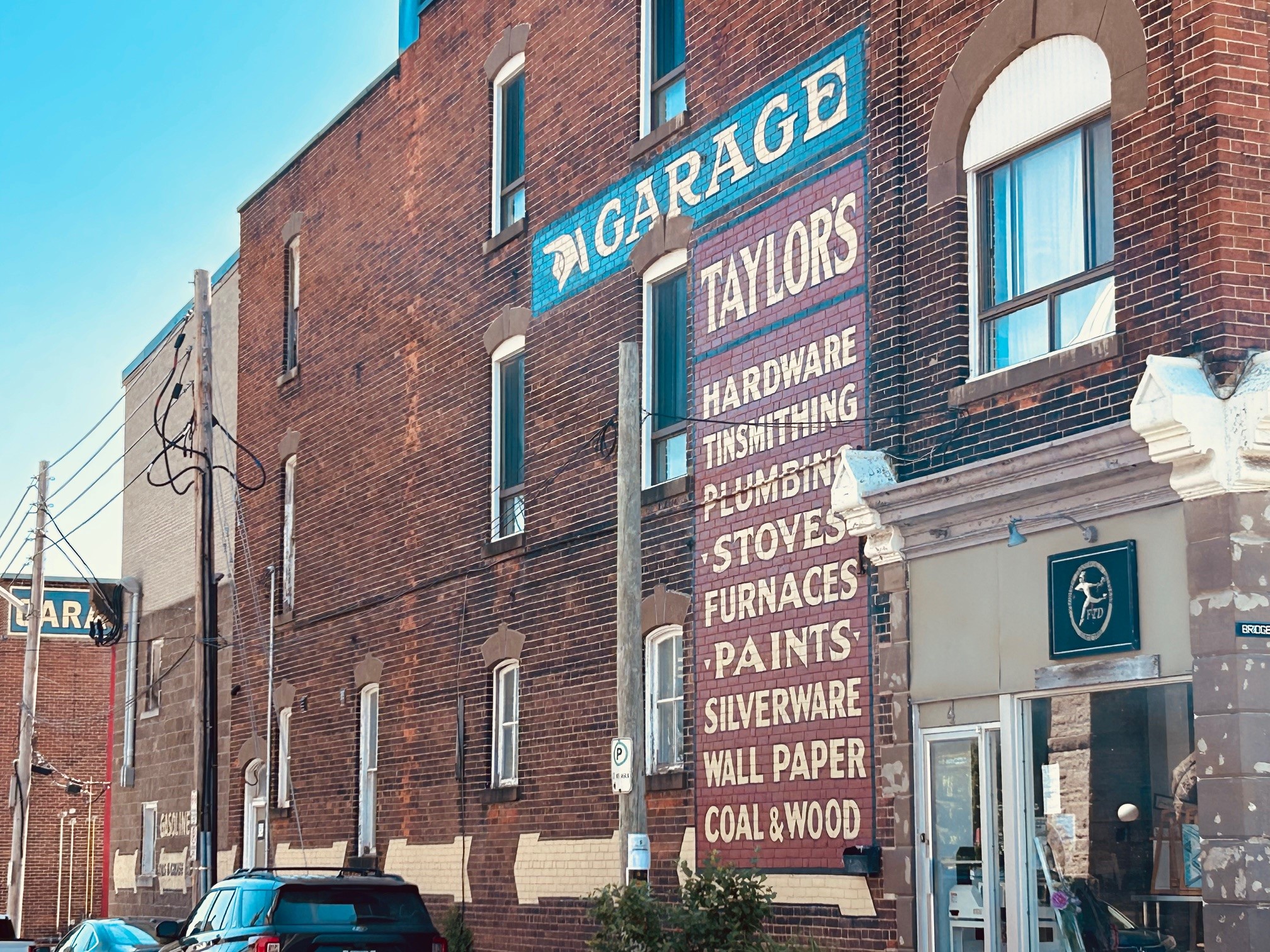 Image of 2 murals, garage and Taylors on the side of a building